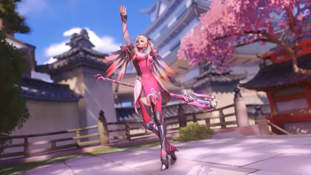 Mercy lève le bras vers le ciel avec son bâton derrière elle.