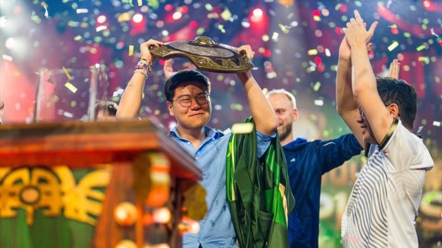 Blitz, coach de Team Liquid, soulève l'Aegis des Champions de Dota 2 alors que des confettis tombent autour de lui lors de TI 2024.