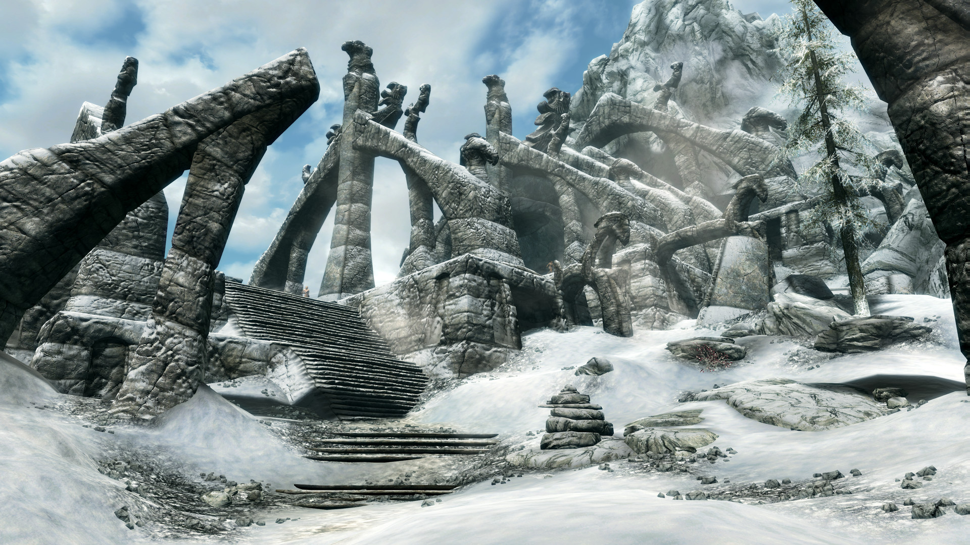 Capture in-game The Elder Scrolls V Skyrim Special Edition : escalier monumental en colimaçon entre des arches de pierre sculptées, paysage enneigé du nord de Skyrim, ambiance mystique.